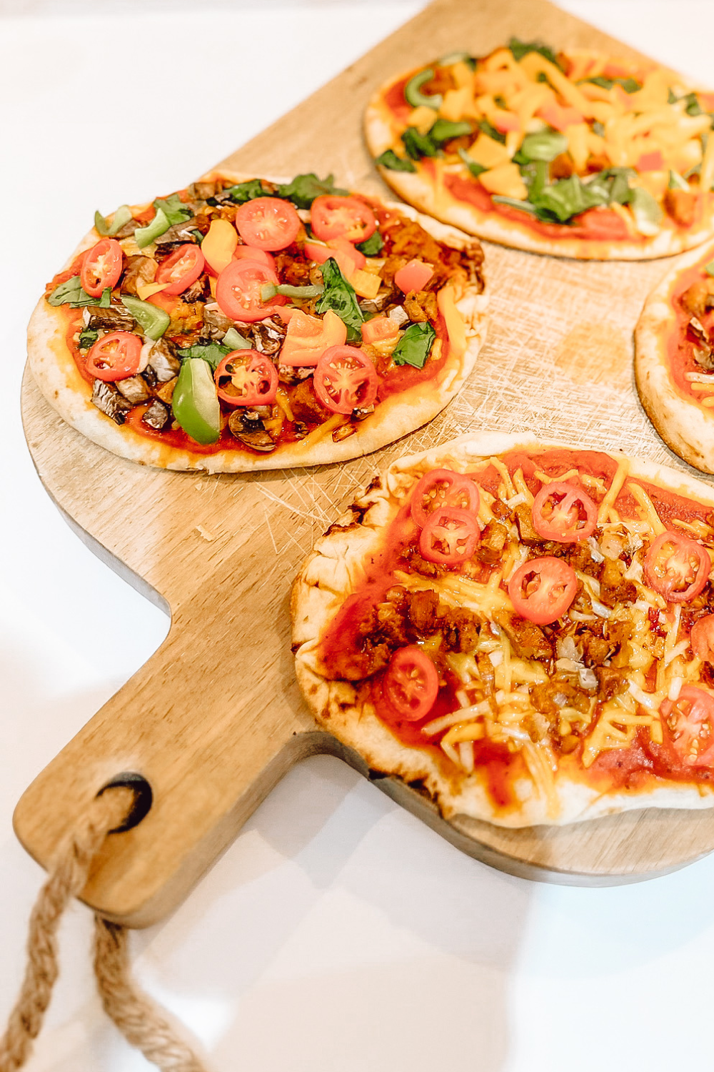 Flatbread naan bread pizza topped with colorful vegetables and vegan mozzarella, a quick family-friendly dinner recipe made at home by a homeschool mom.
